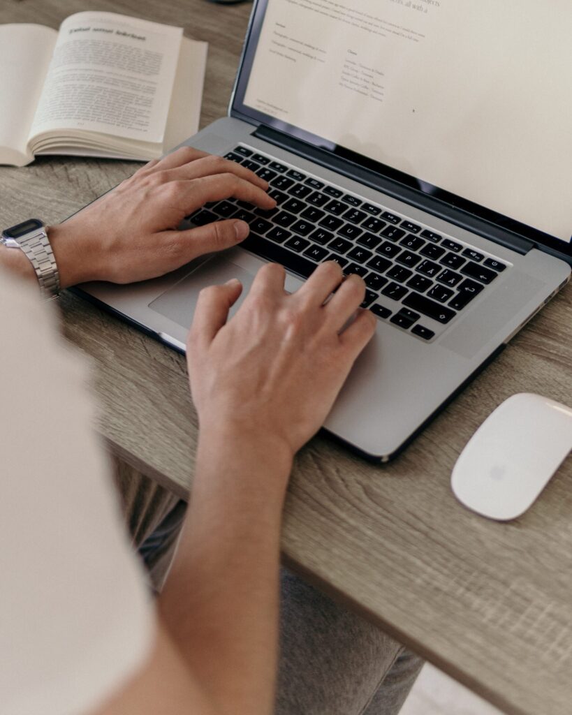 person using macbook pro on brown wooden table